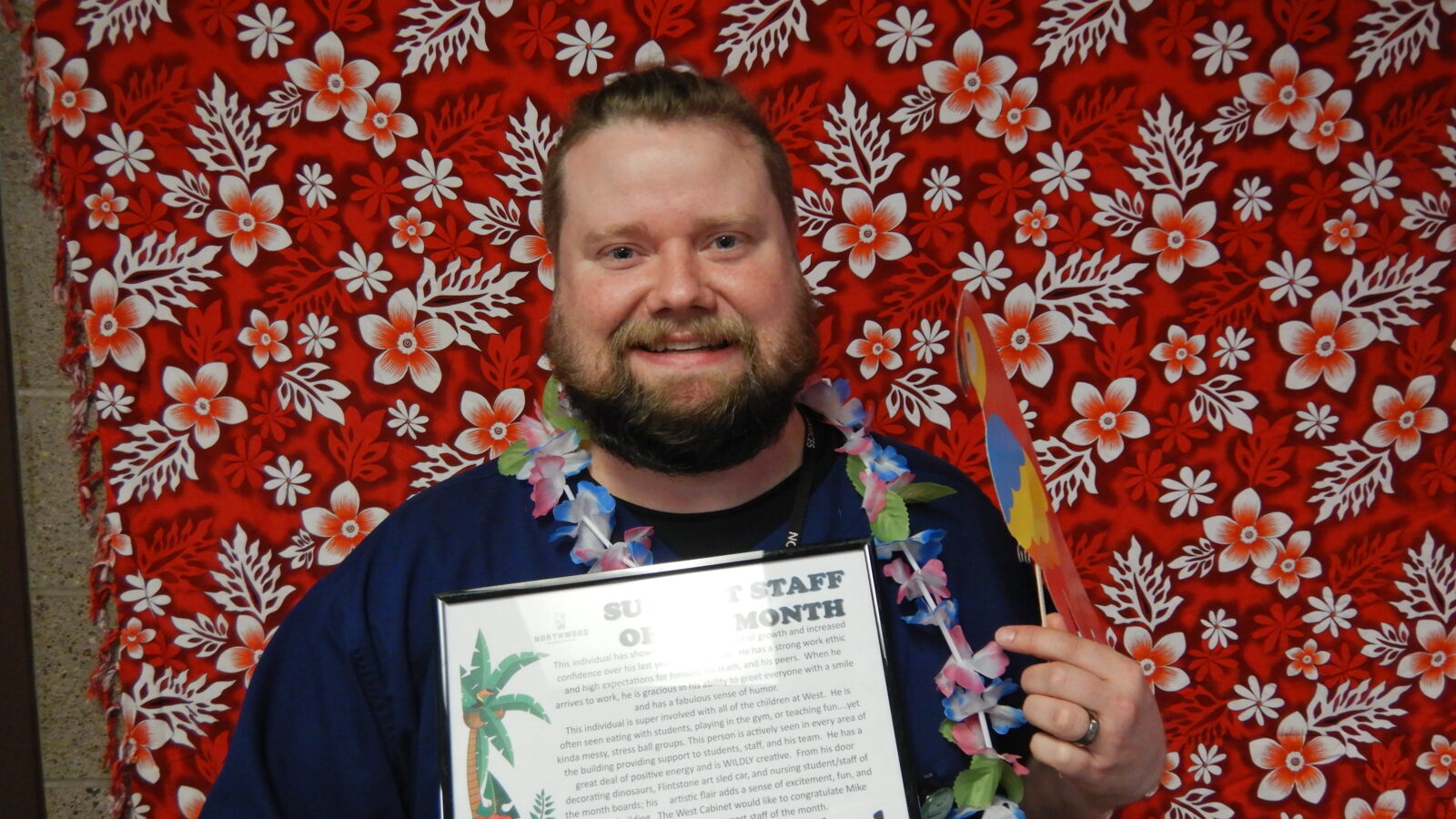 Person winning "Student Staff of the month" in front of floral background